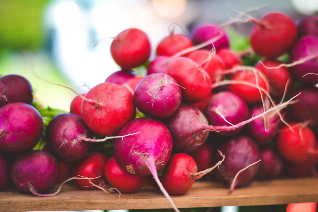 multi-colored 'easter egg' radishes bundled together and displayed on a wooden board