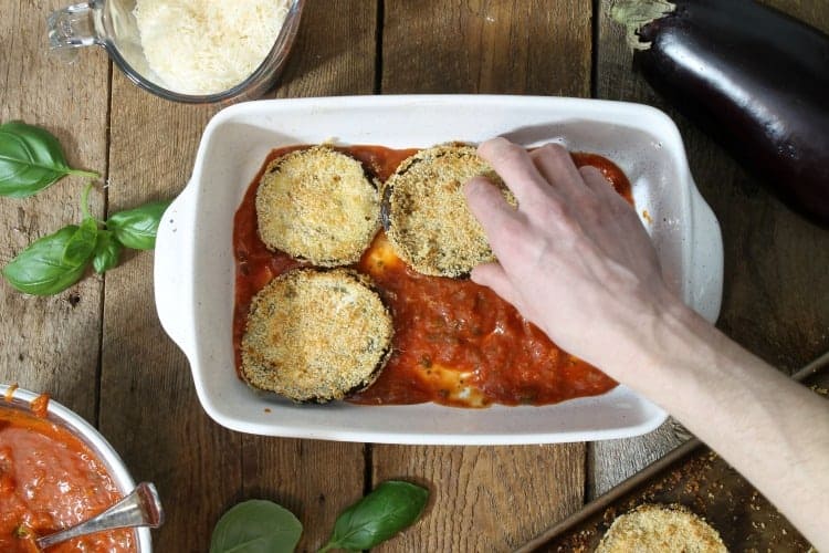 layering baked eggplant slices on the tomato sauce