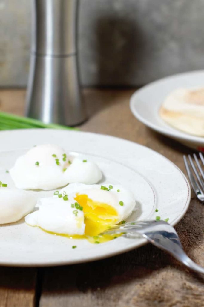 vertical image of a cut open freshly poached egg