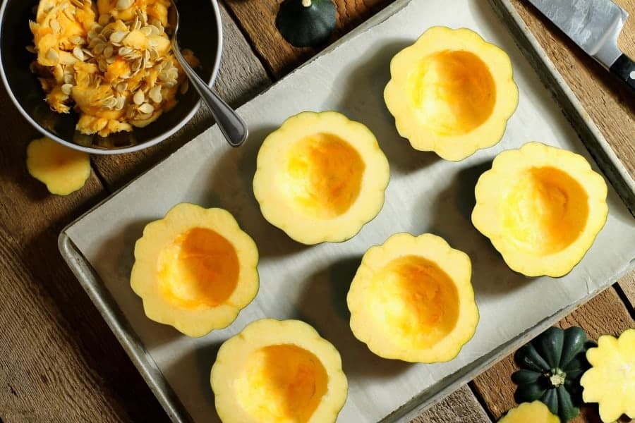 cleaned acorn squash halves on a sheet pan ready to be roasted.