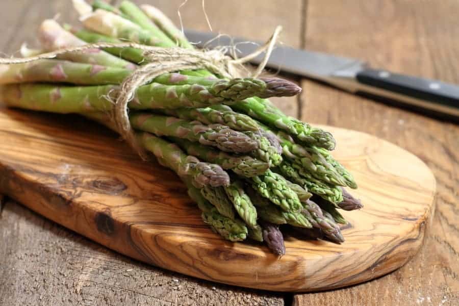 a bundle of fresh cut asparagus on a wooden cutting board