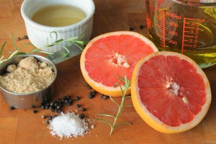 various ingredients including a sliced grapefruit, vinegar, olive oil, and spivces needed to make grapefruit vinaigrette