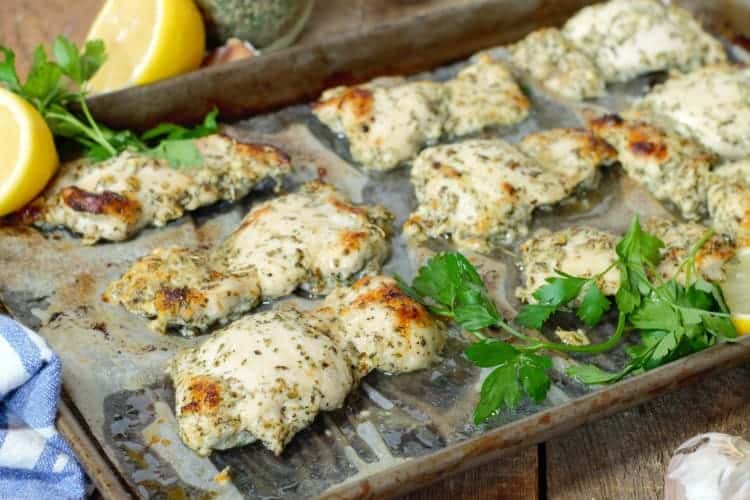 Greek marinated chicken thighs, oven baked on a sheet pan and garnished with lemon and parsley