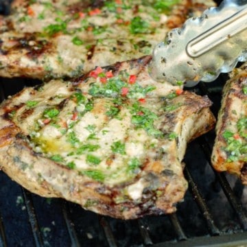 grilled pork chops topped with chimichurri on a bbq grill