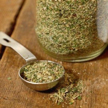 homemade italian seasoning in a measuring spoon on a wooden table