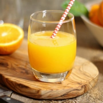 A glass of freshly squeezed orange juice on a wooden board