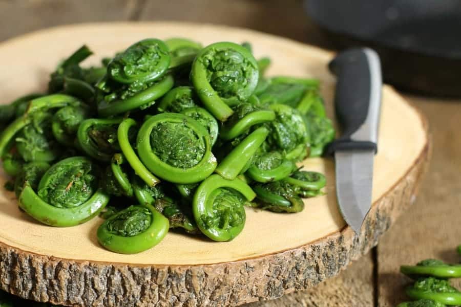 freshkly washed fiddleheads on a wooden cutting board, ready for cooking