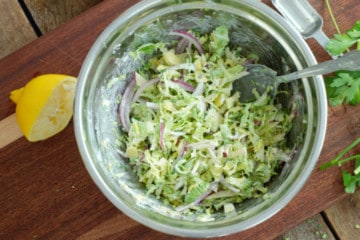 Mixing the raw shaved veggies with the salad dressing