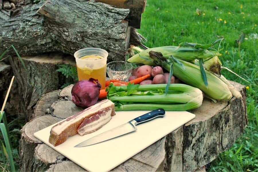 A camp kitchen set up outdoors on a log