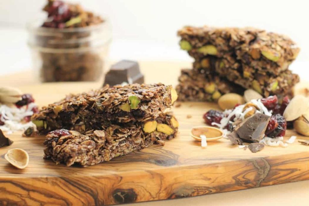 Homemade gluten free Granola Bars on a wooden board surrounded by various ingredients