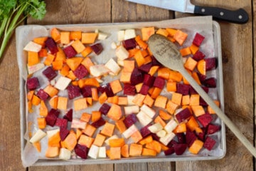 raw root vegetables tossed in oil on a sheet pan