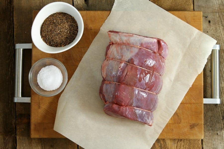 a raw, tied sirloin tip roast on a wooden cutting board